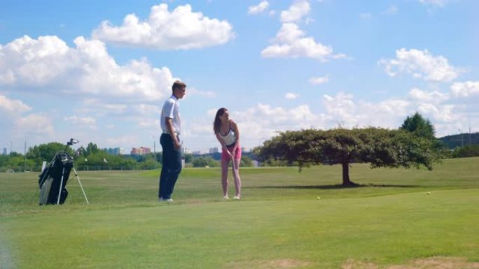女人在男人的监督下打高尔夫球