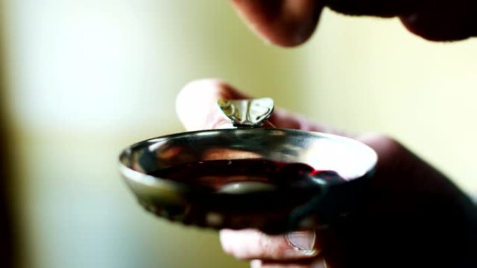 中年侍酒师的慢动作将红酒倒入tastevin中，以判断葡萄酒的成熟度和味道。(特写)