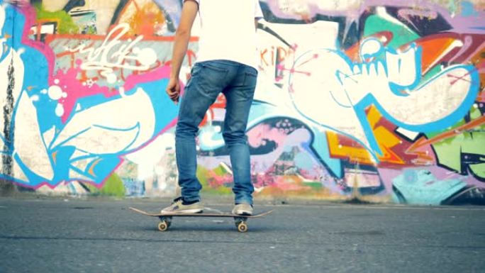 年轻人跳上滑板，开始沿着涂鸦墙骑行