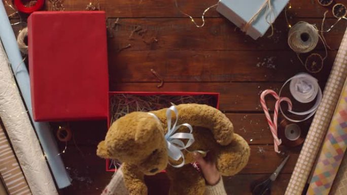 女性双手包装毛绒熊成红色礼品盒