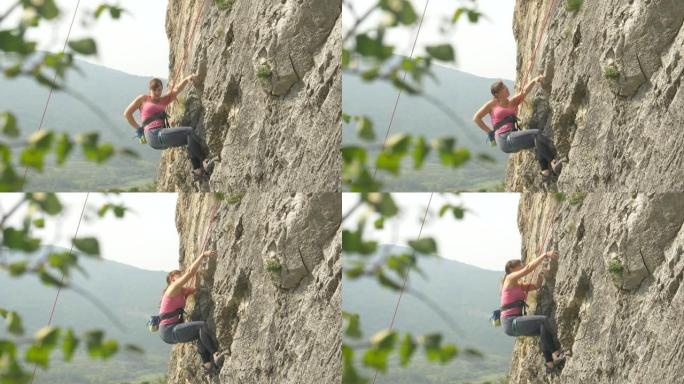 特写: 一个活跃的女人在攀岩爬上巨大的悬崖时的精彩镜头。