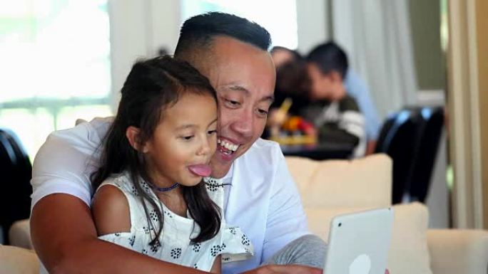 爸爸和女儿在看数字平板电脑时做鬼脸