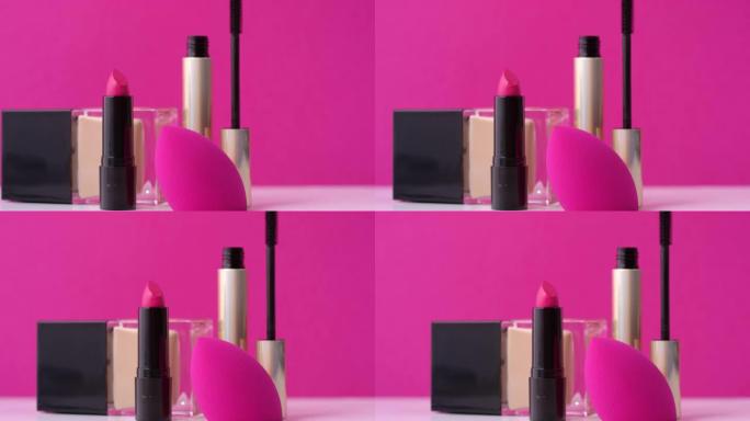 粉红色背景上的装饰化妆品和化妆海绵