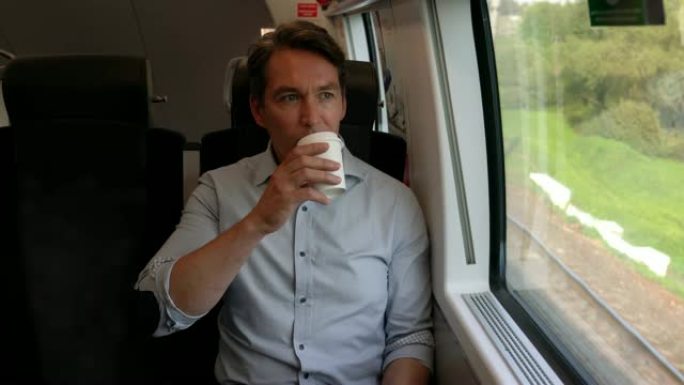 火车上的商人坐着舒适地喝咖啡，一边欣赏窗户的景色