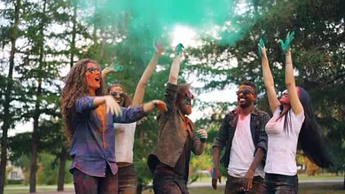多民族朋友的慢动作学生跳和扔油漆粉，然后在明亮的云层中跳舞和大笑。自然、派对和有趣的概念。