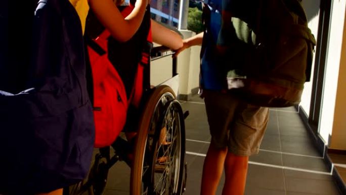 小学生在4k走廊上推着轮椅上的残疾女学生