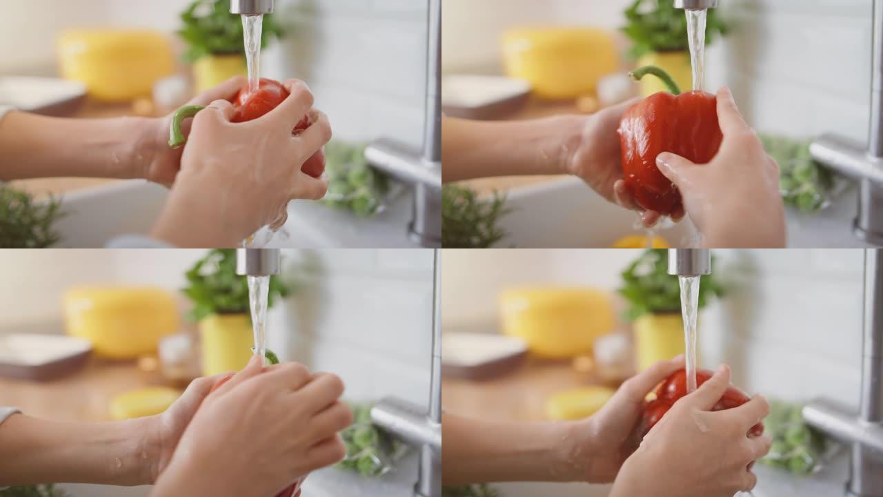 在厨房里: 聪明的小男孩准备沙拉，洗甜椒，其他蔬菜，还有他的手在自来水下的水槽里。特写聚焦儿童的手