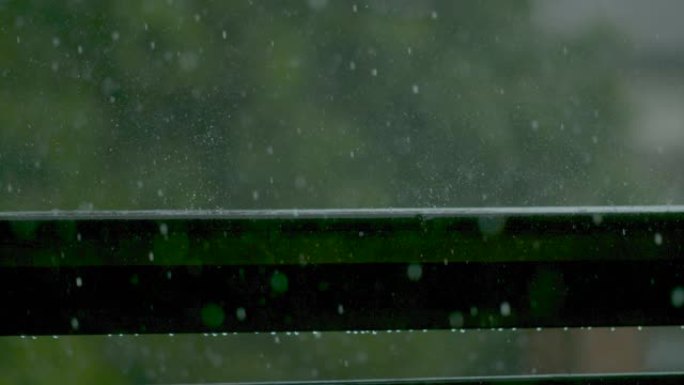 特写: 雨滴落在潮湿的阳台栏杆上的电影镜头。