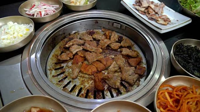 在木炭烤盘上烤猪肉的4k镜头与配菜韩国传统美食，韩国风格和烧烤概念