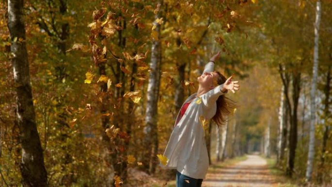 复制空间: 快乐的女人将一堆秋天的彩色叶子高高抛向空中。