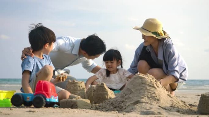暑假的家人一起在海滩上玩沙堡。慢动作。家庭、假期和旅行概念。