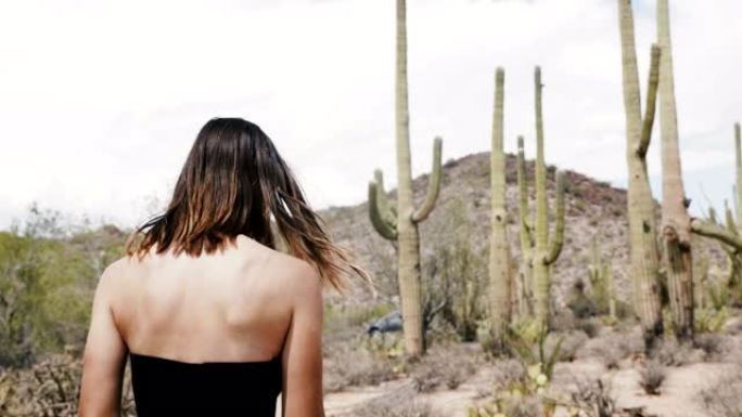 穿着长裙的年轻迷人旅游女人在大仙人掌沙漠国家公园散步的慢动作背景图