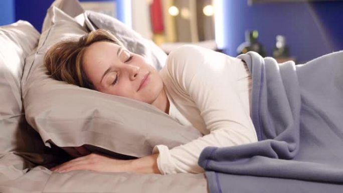 一个女人睡在床上，静静地睡在床上，裹着毯子，让她保持温暖。