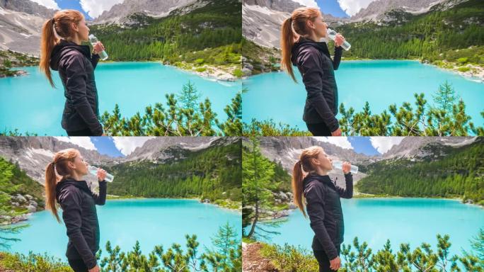 山湖边的女人用可重复使用的水瓶补水