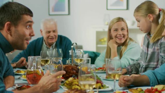 大家庭和朋友在家里庆祝，各种各样的儿童，年轻人和老人聚集在餐桌旁。吃饭、分享食物、喝酒和愉快的交谈。