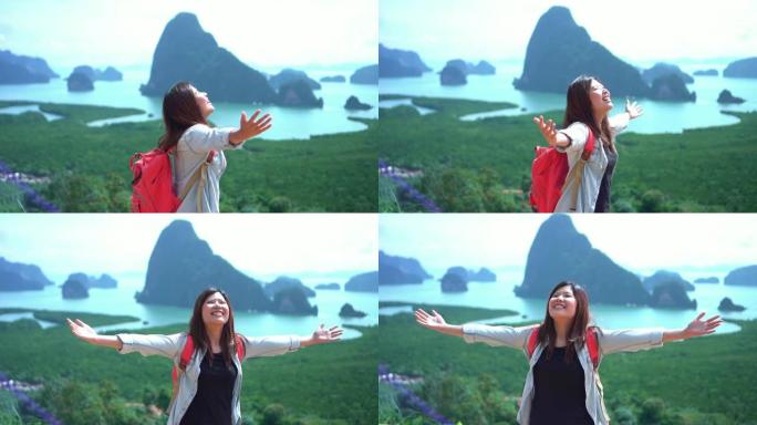 迷人的亚洲女性旅行者的4k慢动作镜头在山顶上举起手臂，在Samed Nang Chee观看风景，感受