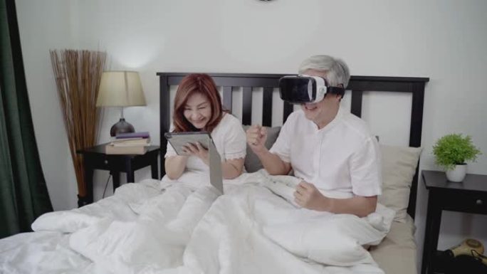 4k分辨率快乐亚洲老年夫妇生活方式技术设备概念，可爱的老年夫妇在家使用VR耳机