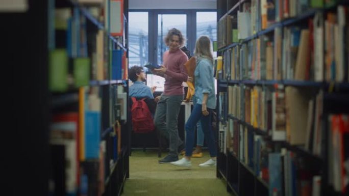 大学图书馆:男孩在书桌上使用个人电脑，与女同学交谈，女同学解释，帮助他完成课堂作业。专注的学生一起学