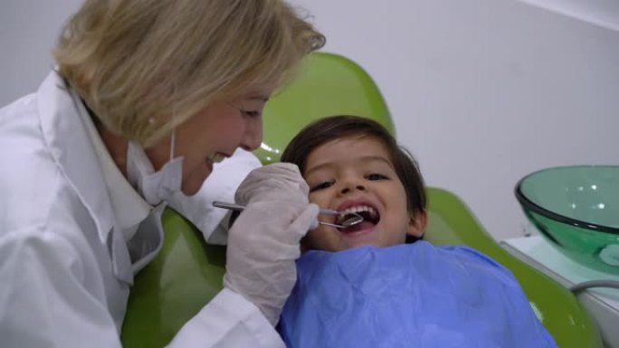 爱心女牙医很调皮地检查一名男儿科患者的牙齿