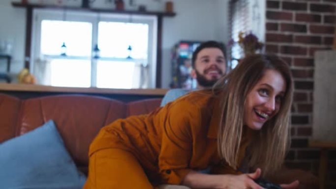 开朗的年轻白人夫妇互相玩游戏机，在家里一起玩慢动作。