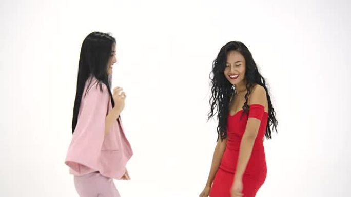 两个亚洲女人在白色背景下疯狂跳舞。有聚会、庆祝、享受和新年概念的人。慢动作。