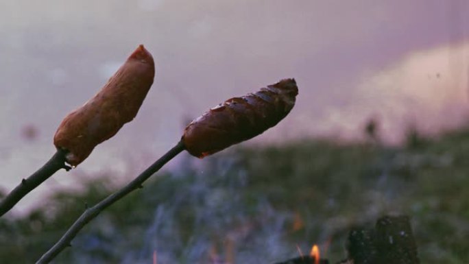 CU香肠在篝火上用棍子烹饪