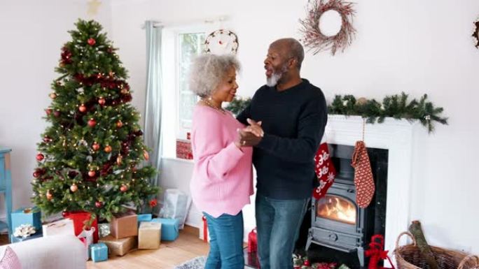 高级黑人夫妇在客厅跳舞，为圣诞节装饰，四分之三长度的视图，手持