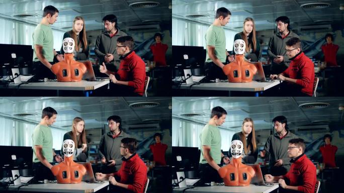 四名工程师与人形机器人，机器人一起工作。