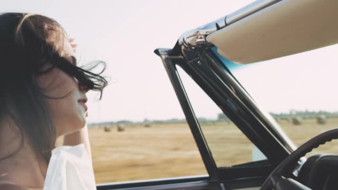 CU美丽的年轻女子驾驶敞篷车沿着阳光明媚的乡村田野