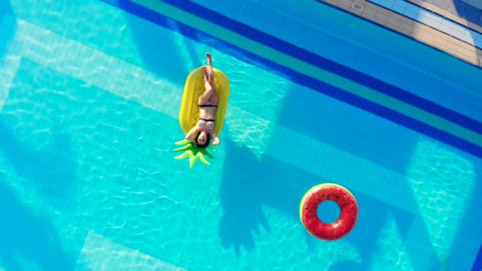 一个女孩在旅馆游泳池里休息，那里有橡胶圈。