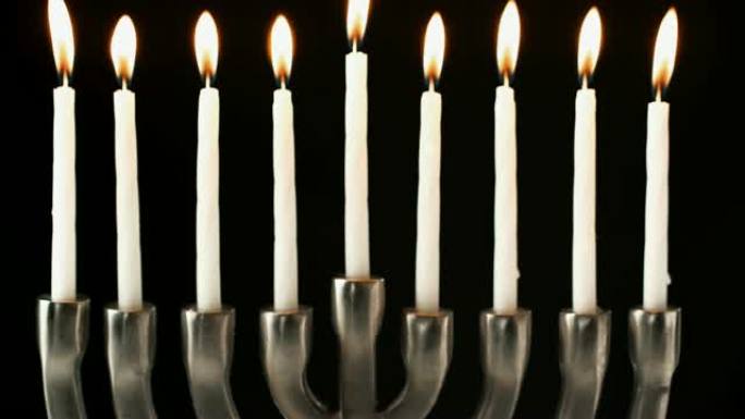 犹太烛台烛台的倾斜镜头，黑色背景下点燃蜡烛