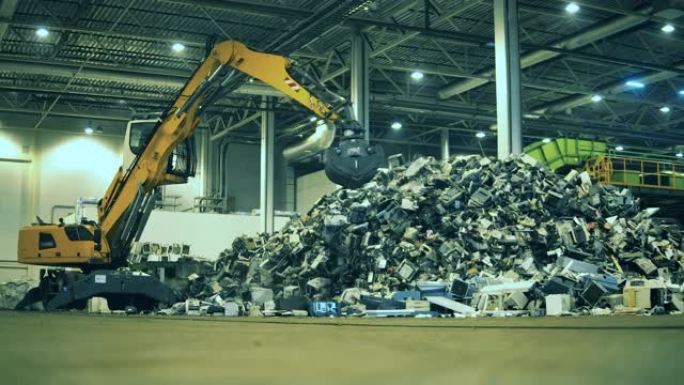 垃圾，垃圾，废物回收工厂。挖掘机在室内垃圾场工作