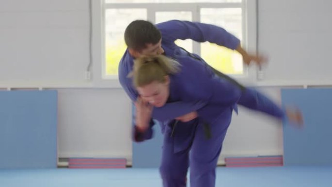 女子柔术运动员在与男伴一起训练时进行髋关节投掷