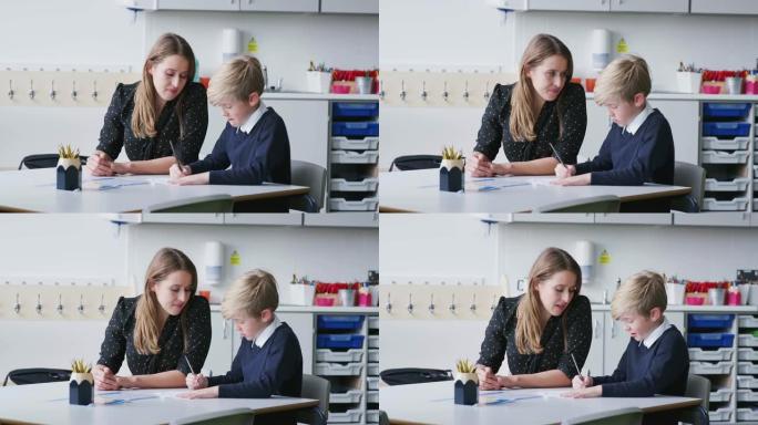 女小学老师和男生在教室里一对一工作，低头，特写