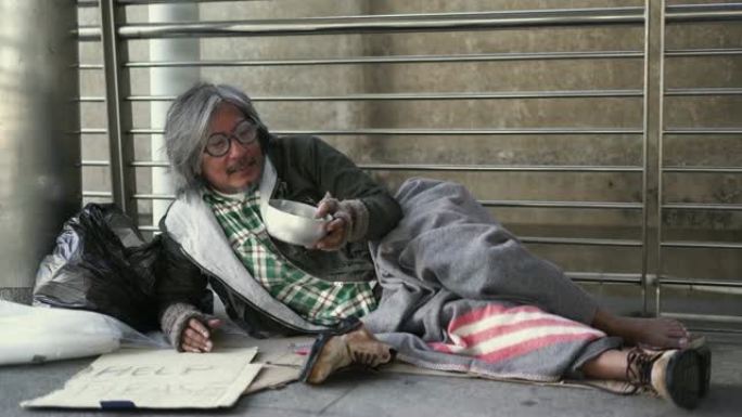 人们把钱捐给人行道上无家可归的乞讨碗。