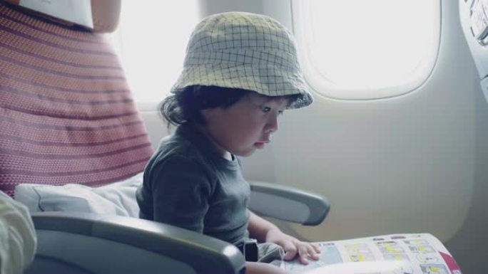 亚洲男婴飞机飞行阅读书。