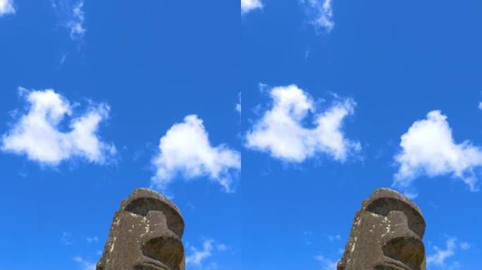 低角度: 晴天，浮肿的白云在大型摩艾雕塑上漂移