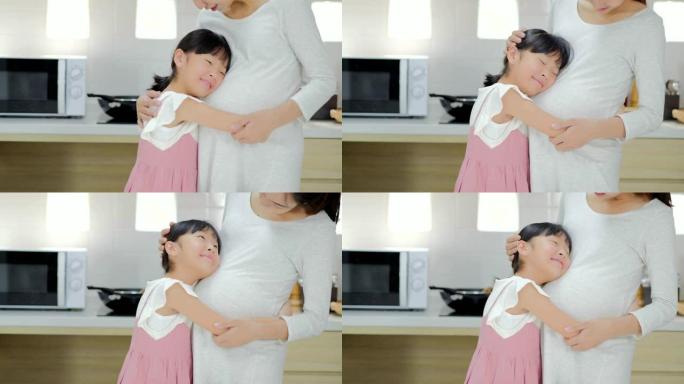 孕妇和一个孩子拥抱。怀孕的母亲和女孩正在家里聊天和共度时光。怀孕，家庭，父母身份，准备和期望概念。怀