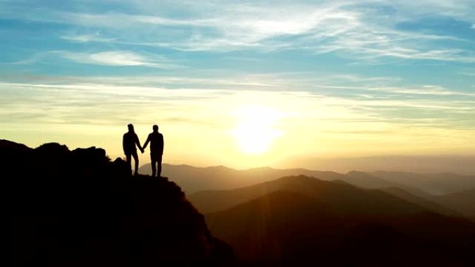 男人和一个女人站在山上，看着美丽的日出