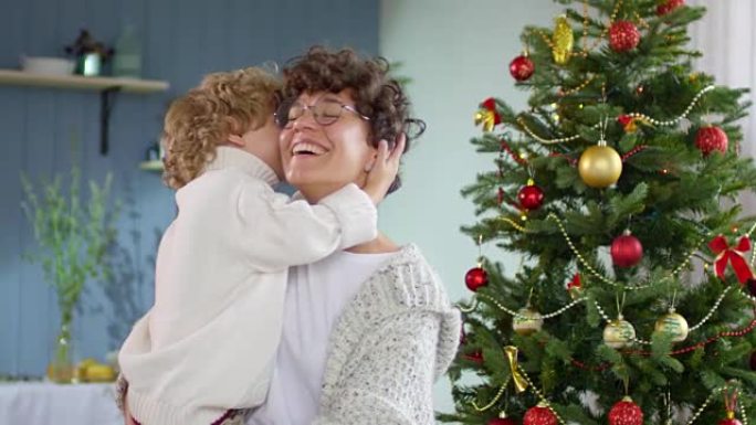 母亲和小男孩在圣诞树上摆姿势