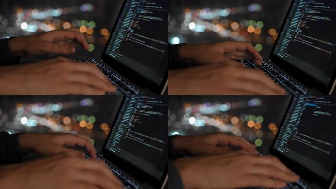 程序员以美丽的夜窗为背景编写网站开发代码，在夜窗中，在散焦中可以看到城市的灯光。