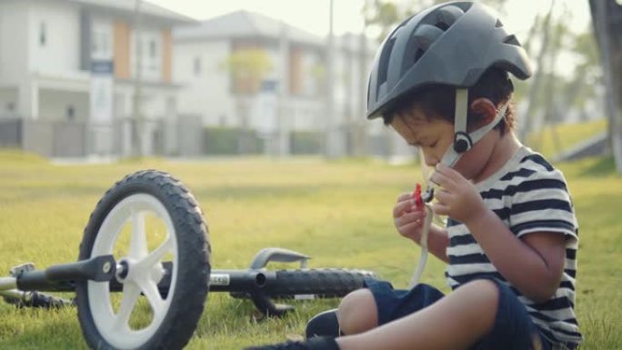 在泰国公园的一个阳光明媚的日子里，亚洲小男孩带着运动头盔在外面骑自行车