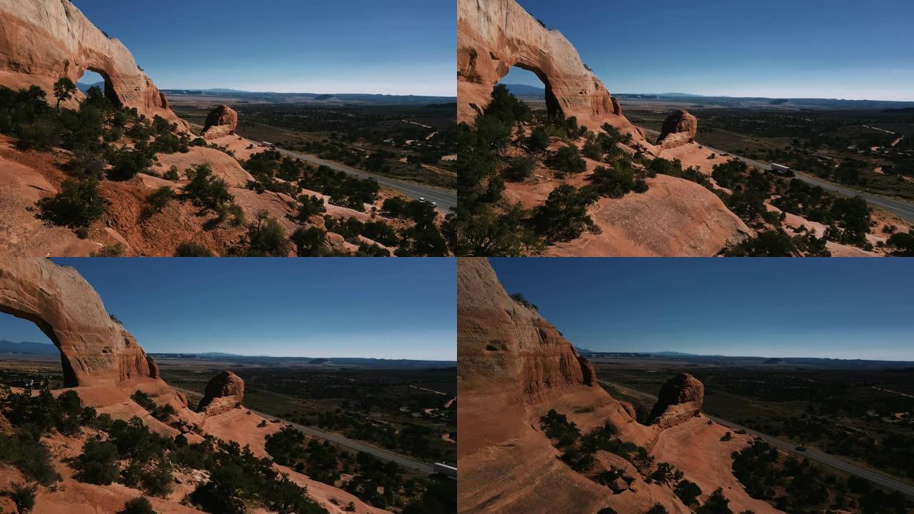 无人机在大岩层附近飞行，大洞覆盖着灌木丛，游客可以欣赏到山区沙漠的景色。