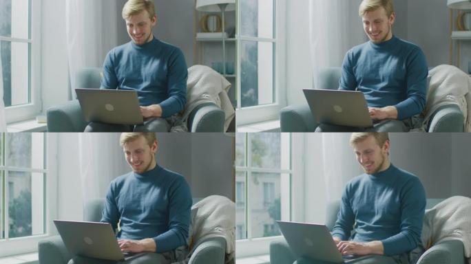 英俊的金发年轻男子坐在他舒适的客厅的椅子上在笔记本电脑上工作的肖像。创意自由职业者在家放松，浏览互联