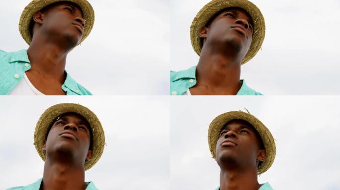 站在海滩4k上戴着帽子的非洲裔美国人的低角度视角