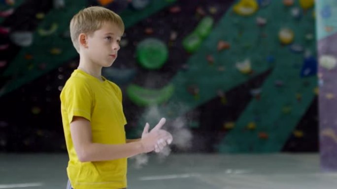 高加索少年在攀岩体育馆里粉刷粉笔