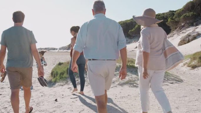 暑假期间，多代家庭在前往海滩的路上沿着沙质小路行走