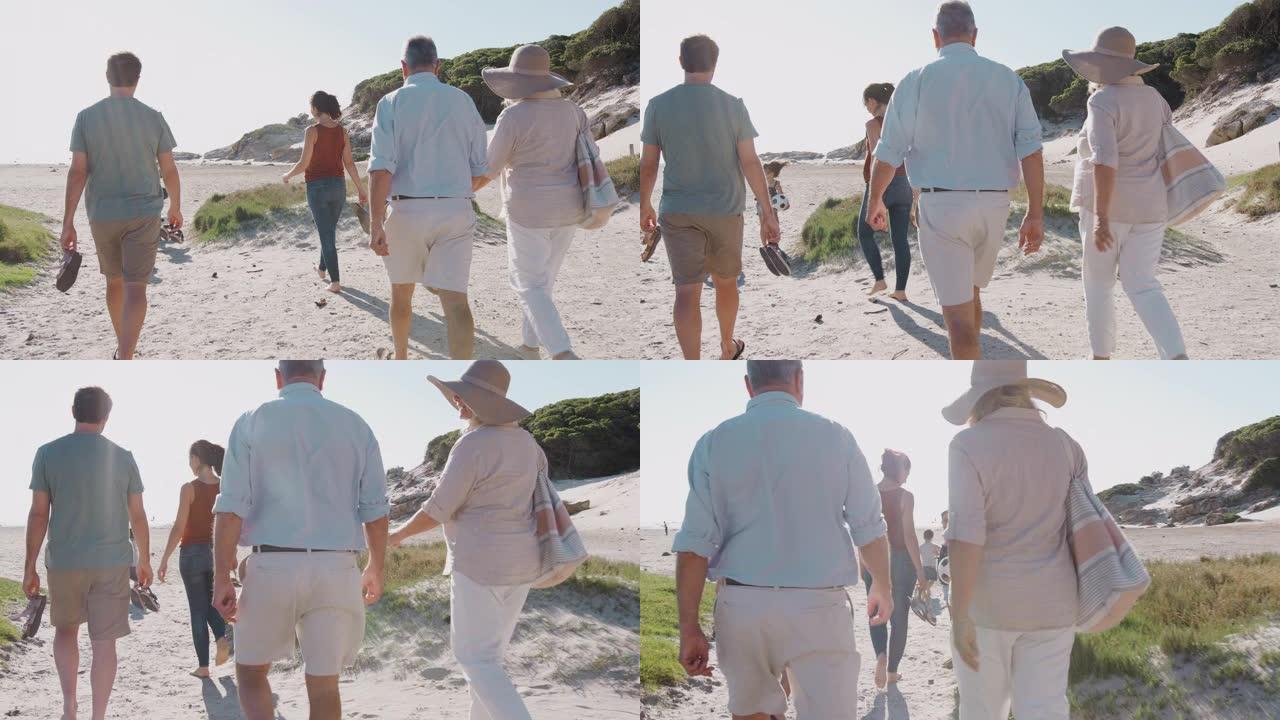 暑假期间，多代家庭在前往海滩的路上沿着沙质小路行走