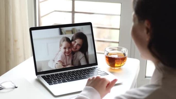 女人妈妈在电脑屏幕上视频呼叫女儿和保姆