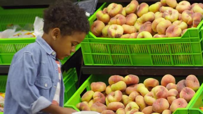小男孩在超市选择桃子